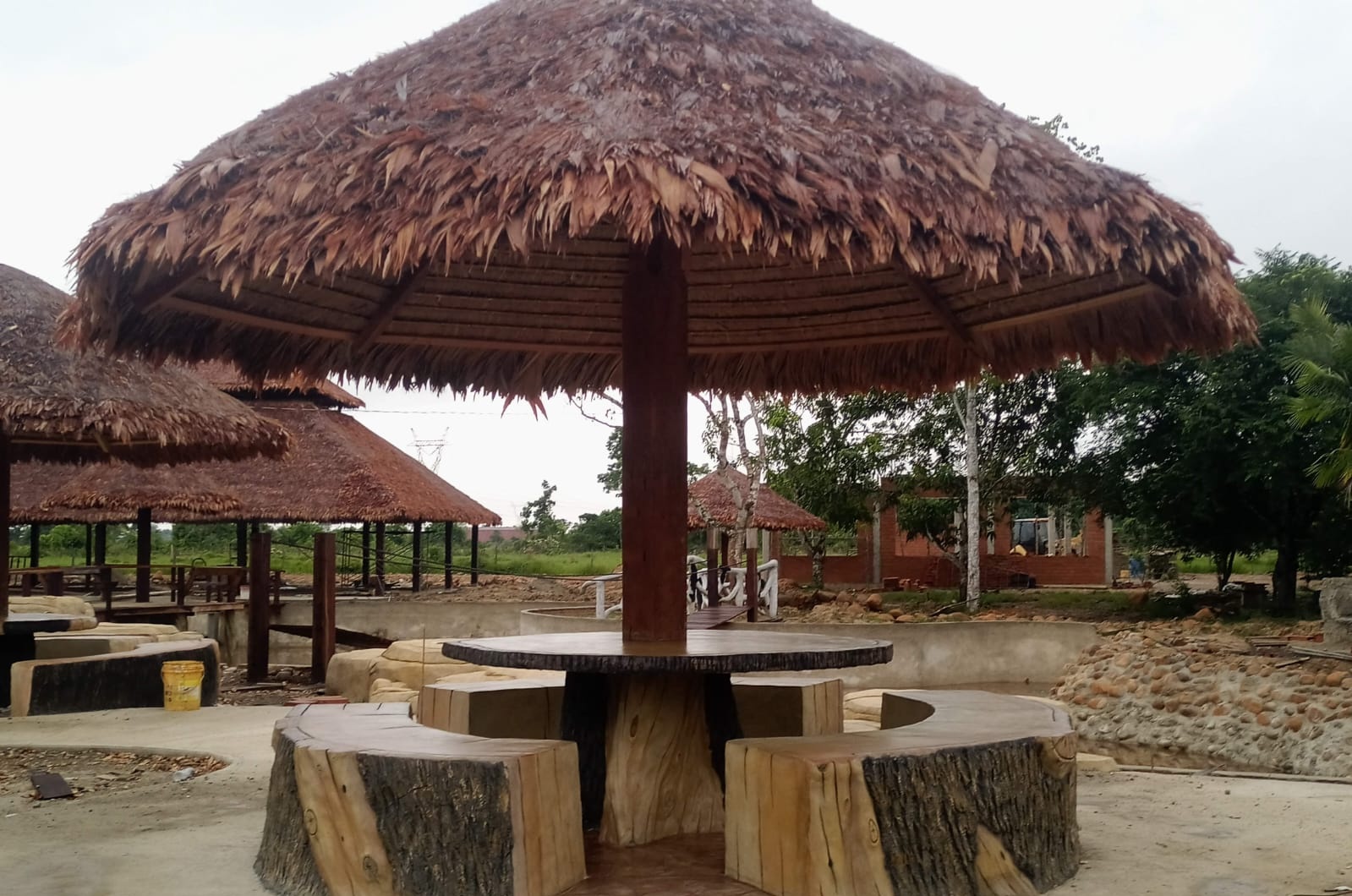 Sombrilla tropical con asientos tallados en concreto símil madera